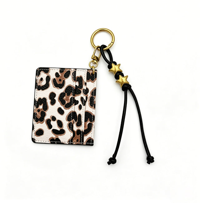 Leopard-print card holder keyring with black knotted cords and gold-tone star beads.