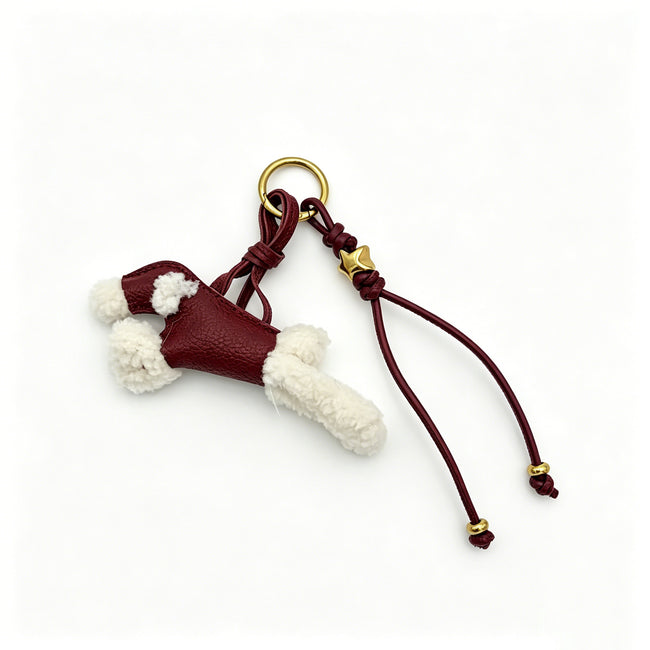 Burgundy poodle-shaped keyring with cream fluffy details, a gold-tone star bead and dangling cords.