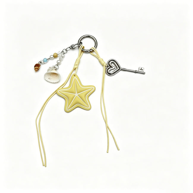 Yellow star keyring with dangling cords, shell charms and a silver-tone heart-topped key.