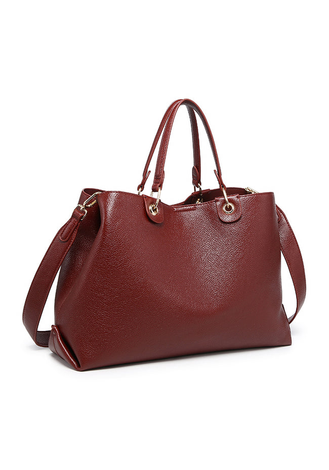 Angled view of a burgundy tote bag with twin handles, a shoulder strap and gold-tone hardware