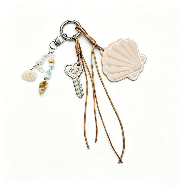 Beige scallop-shell keyring with tan cords, small shell charms and a heart-shaped key charm.