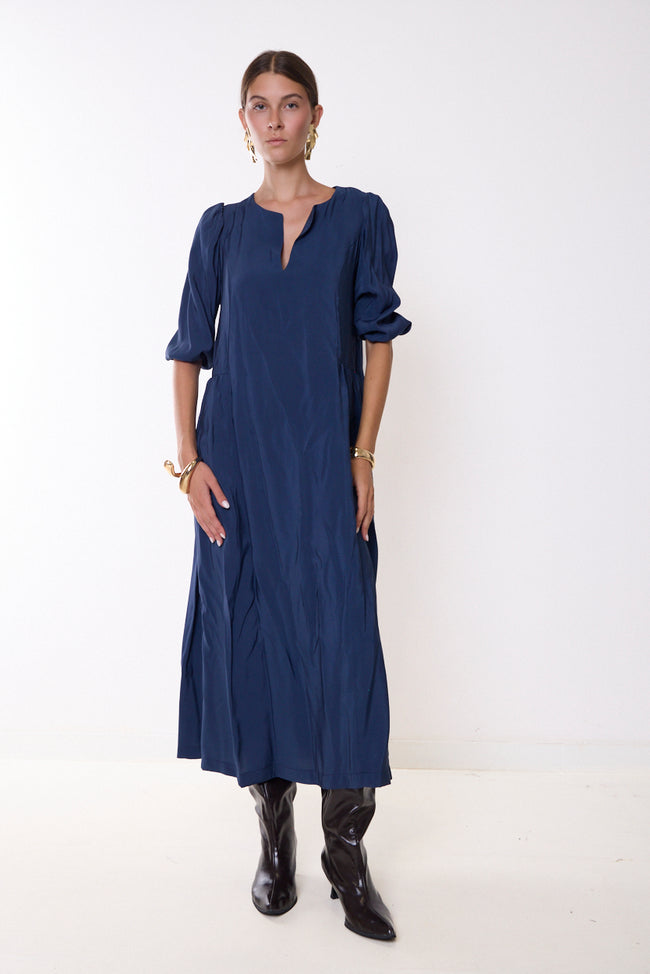 Dark navy blue split-neck long dress with puff sleeves, gathered sleeve ends and side gathering; boots and jewellery styled separately