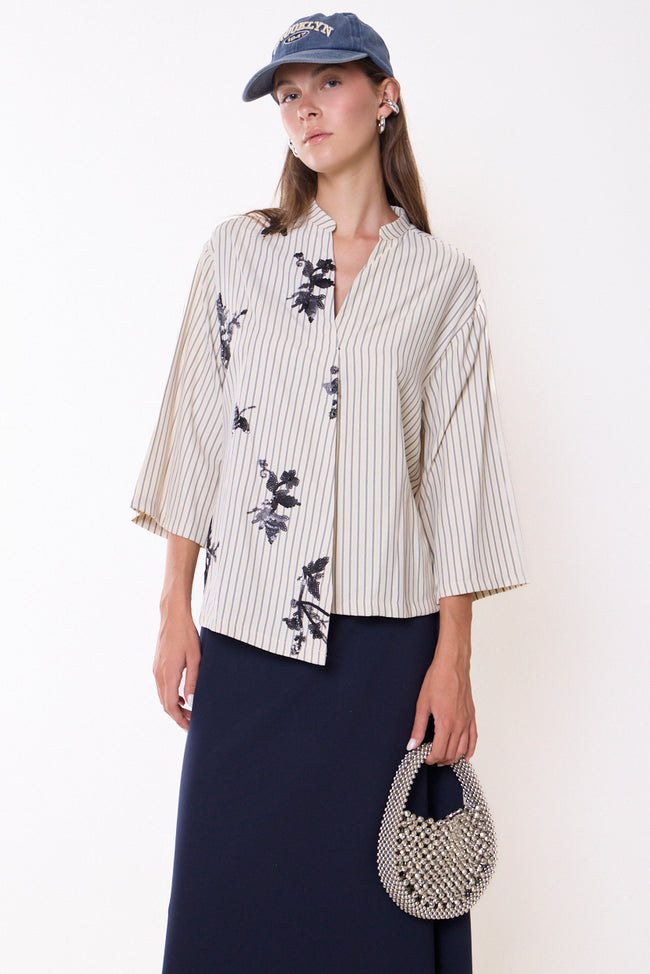 White with fine grey vertical stripes, band-collar button-front shirt with wide cropped sleeves and black floral sequin motifs; skirt, cap and bag styled separately