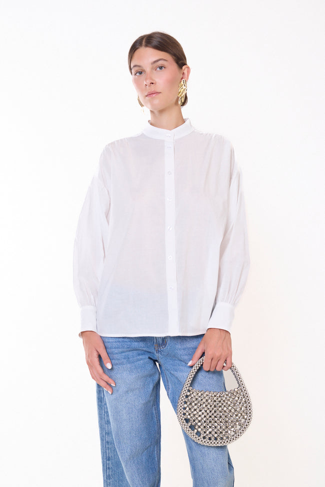 White cotton band-collar button-front shirt with long gathered sleeves, broad cuffs and relaxed silhouette; jeans, bag and jewellery styled separately