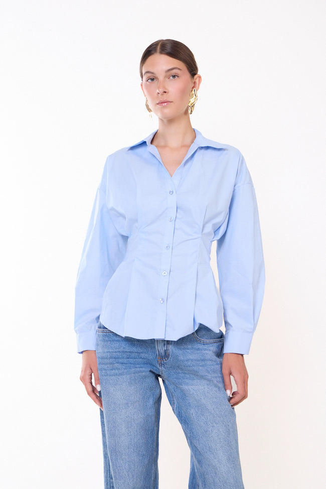 Light blue pointed-collar cotton button-front shirt with shaped waist, long sleeves, button cuffs and curved hem; jeans and jewellery styled separately