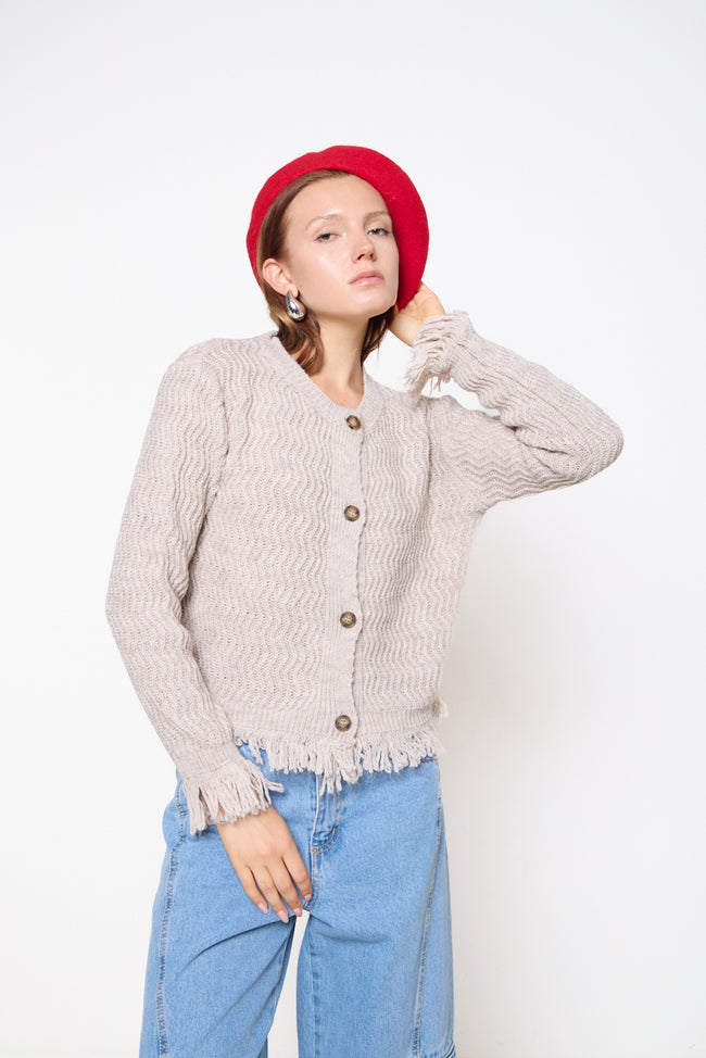 Cream wavy-textured round-neck knit cardigan with front buttons, long sleeves and fringed cuff and hem edges; jeans and accessories styled separately