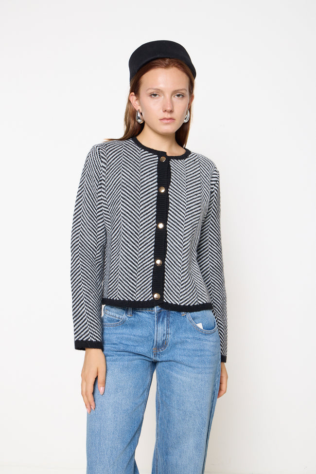 Black and cream chevron-pattern knit cardigan with round neckline, front buttons and contrasting ribbed neckline, button placket, cuffs and hem; jeans, beret and earrings styled separately