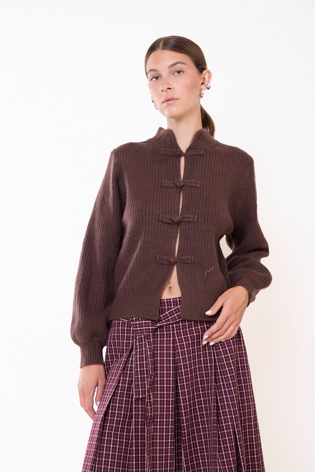 Coffee brown ribbed stand-collar knit cardigan with front knotted loop fastenings, long sleeves and ribbed cuffs and hem; checked trousers, cap and accessories styled separately