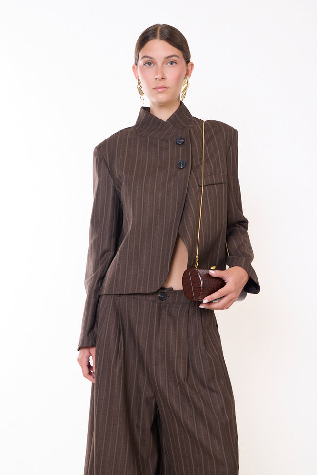 Coffee brown pinstripe fine-pinstripe stand-collar blazer with asymmetric overlapping front, two front buttons, chest pocket detail and long sleeves; trousers or Bermuda shorts, bag and jewellery styled separately