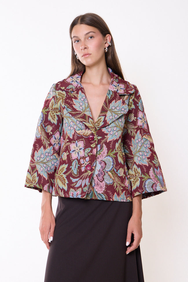 Bordeaux ground with multicoloured flowers floral jacquard blazer with notched lapels, two front buttons, flared cropped sleeves and short silhouette; skirt or jeans styled separately