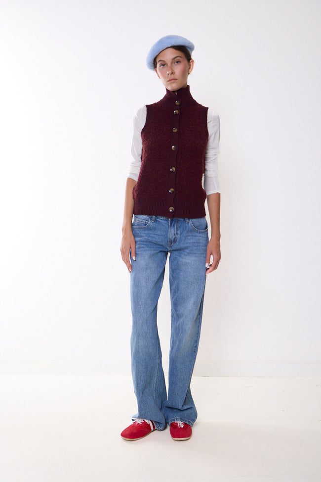 Bordeaux wine textured high-neck button-front knitted vest with ribbed collar, placket and hem; white long-sleeve top styled separately