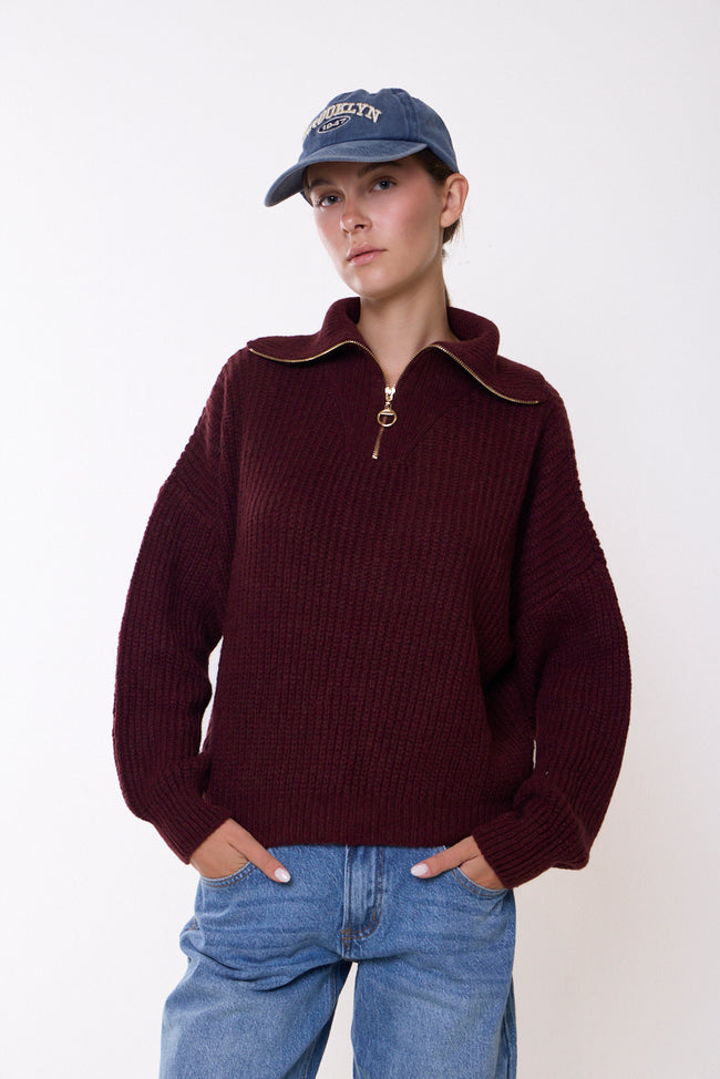 Bordeaux wine ribbed high-neck quarter-zip knit sweater with ring zip pull, long sleeves and ribbed cuffs and hem; jeans and earrings styled separately