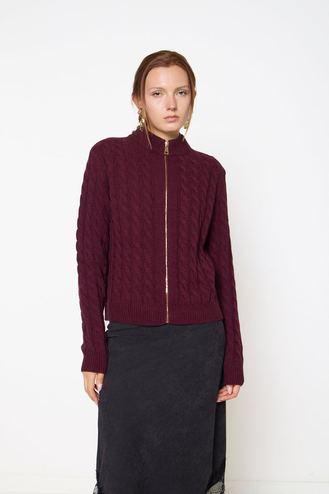 Bordeaux wine cable-knit zip-front cardigan with stand collar, long sleeves and ribbed cuffs and hem; lace-trim skirt and earrings styled separately