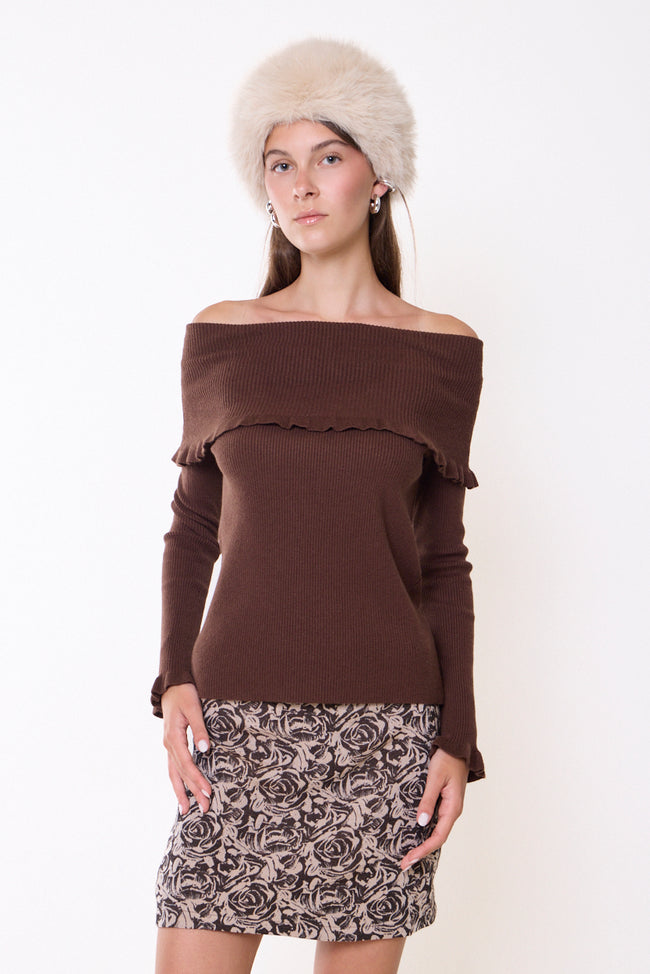 Coffee brown off-shoulder ribbed knit sweater with broad foldover neckline, ruffled neckline edge, long sleeves and ruffled cuffs; patterned mini skirt, hat and bangles styled separately