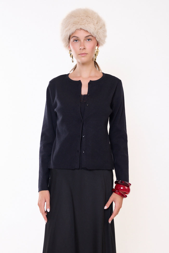 Black fine-knit round-neck button-front cardigan with long sleeves and shaped silhouette, buttoned front view; lace-trim top, skirt, hat and jewellery styled separately