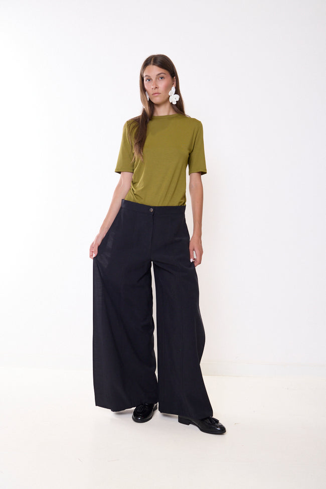 Black dark-navy-toned wide-leg full-length trousers with front button and plain front panels; short-sleeve top and shoes styled separately