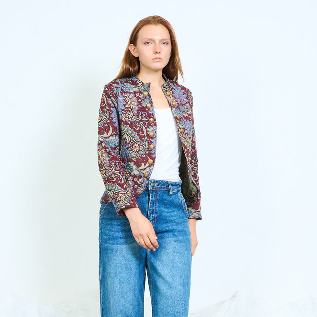Bordeaux ground with multicoloured paisley cropped collarless paisley jacquard jacket with front buttons and long sleeves; plain top, jeans and shoes styled separately