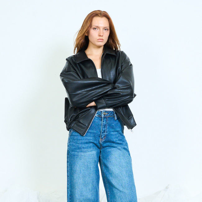 Black roomy faux-leather zip jacket with shirt collar, long voluminous sleeves, side pocket openings and gathered back hem; plain top, jeans and shoes styled separately