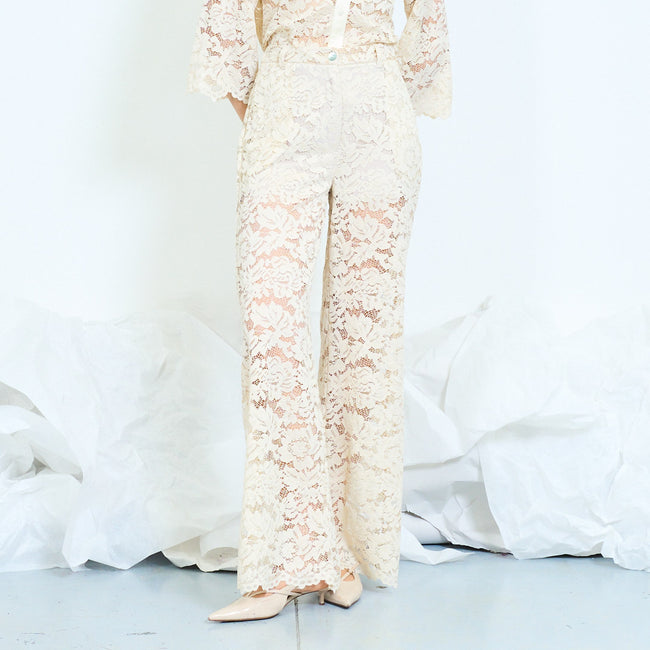 Cream wide-leg floral lace trousers with front button, belt loops, side pocket openings, semi-sheer legs and scalloped hems; coordinating lace shirt and shoes styled separately