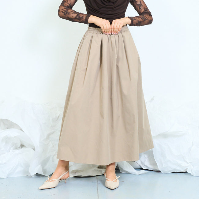 Beige long gathered skirt with broad shirred waistband, side pocket openings and flared silhouette; lace blouse or plain camisole and shoes styled separately