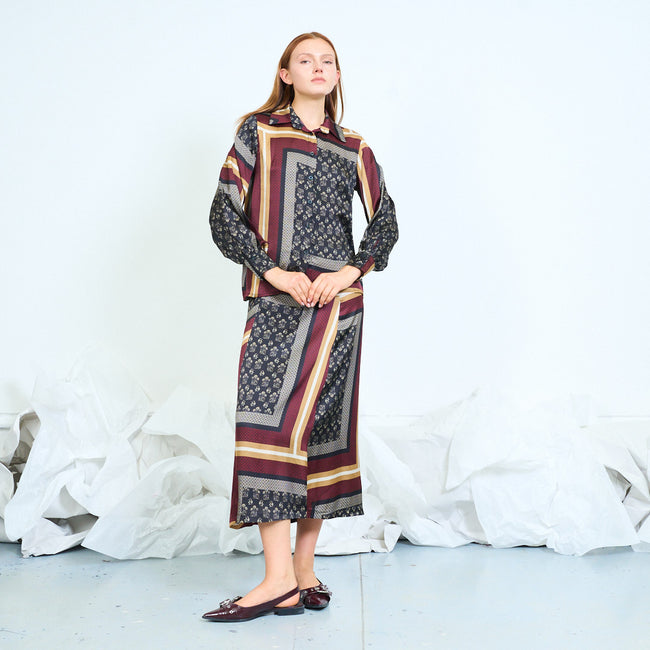 Black ground with burgundy, cream and gold-toned framed floral and geometric patchwork-print shirt with pointed collar, front buttons and long balloon sleeves; coordinating print skirt and shoes styled separately