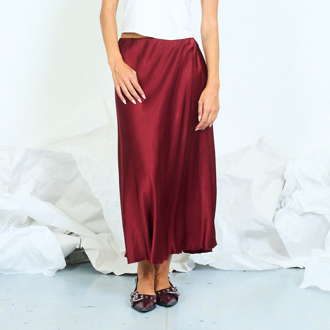 Front view of a glossy burgundy long skirt with a softly flared hem.