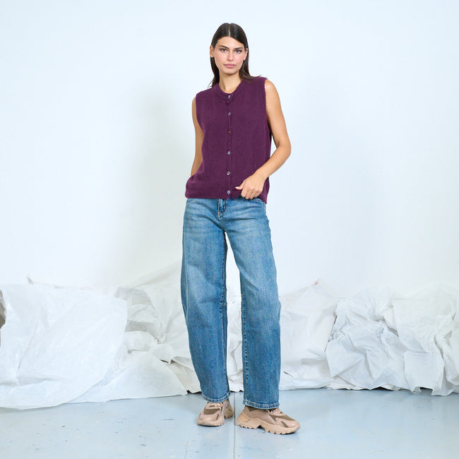 Model wearing a purple button-front knit vest with blue jeans