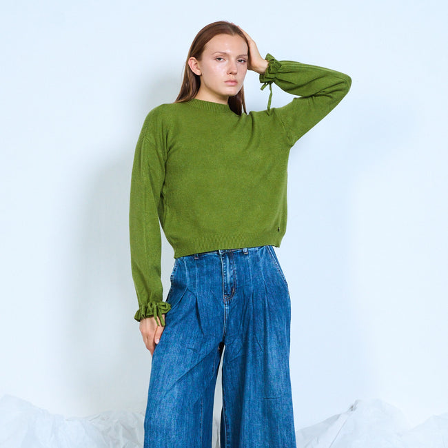 Model wearing a green crewneck sweater with gathered tie cuffs.