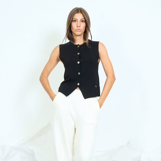 Front view of a black button-front sleeveless vest with a shaped hem.