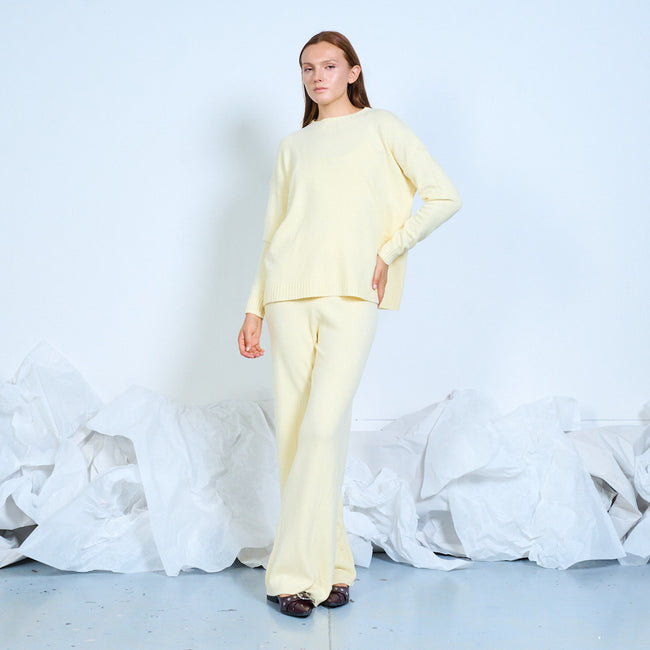 Full-length view of a pale yellow crewneck sweater and matching wide-leg trousers.