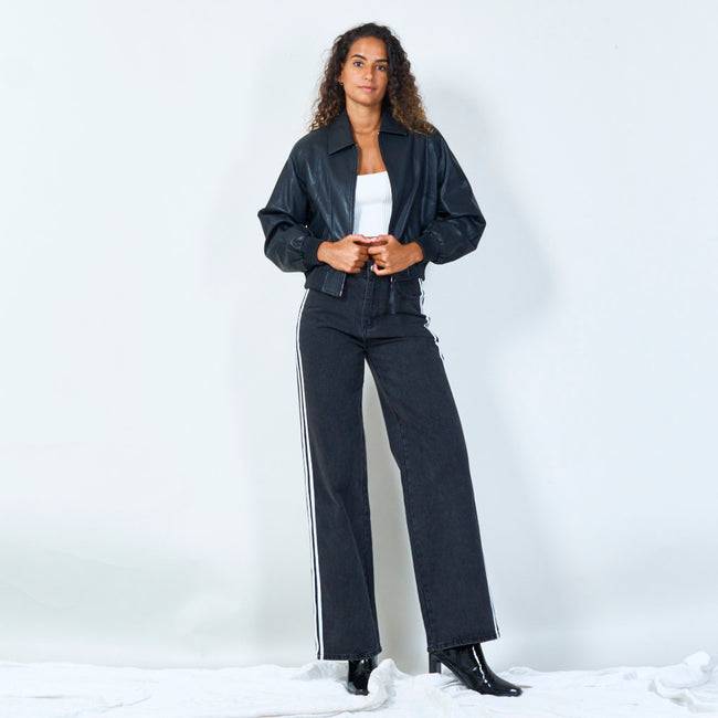 Full-length view of a black cropped zip-front jacket worn with wide-leg jeans.