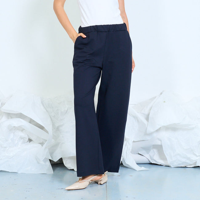 Dark navy blue elastic-waist wide-leg trousers with side pockets and full-length legs; white camisole and shoes styled separately