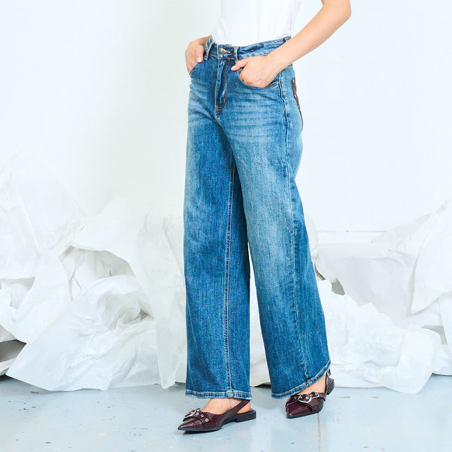 Angled view of faded blue wide-leg jeans with long vertical leg seams.