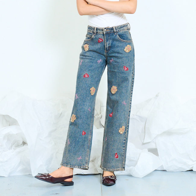 Front view of faded blue wide-leg jeans with teddy bear and heart motifs.