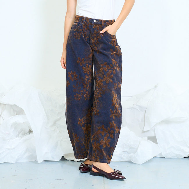 Front view of dark blue barrel-leg jeans with brown floral patterns.