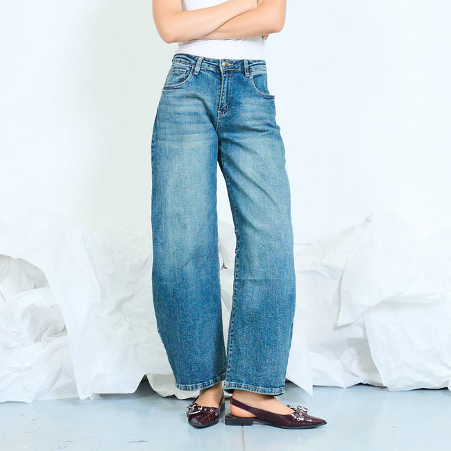 Front view of faded blue barrel-leg jeans with a curved silhouette.