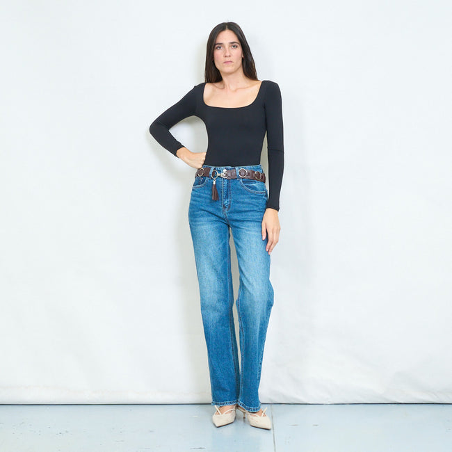 Full-length view of a model wearing blue straight-leg jeans with a brown ring belt and tassel.