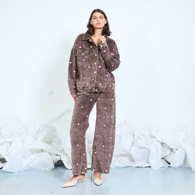 Model wearing washed brown polka-dot trousers with a matching jacket.