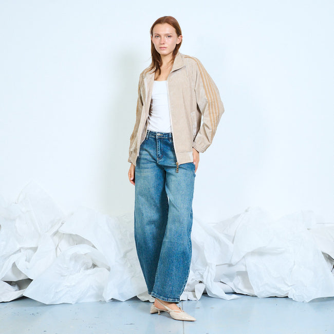 Model wearing a beige zip-front jacket with striped sleeves and wide-leg jeans.
