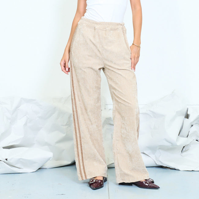 Front view of beige wide-leg textured trousers with side stripes.