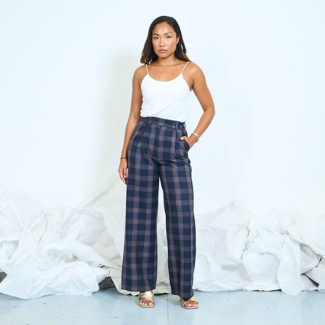 Model wearing navy plaid wide-leg trousers with a white camisole and gold-tone sandals.