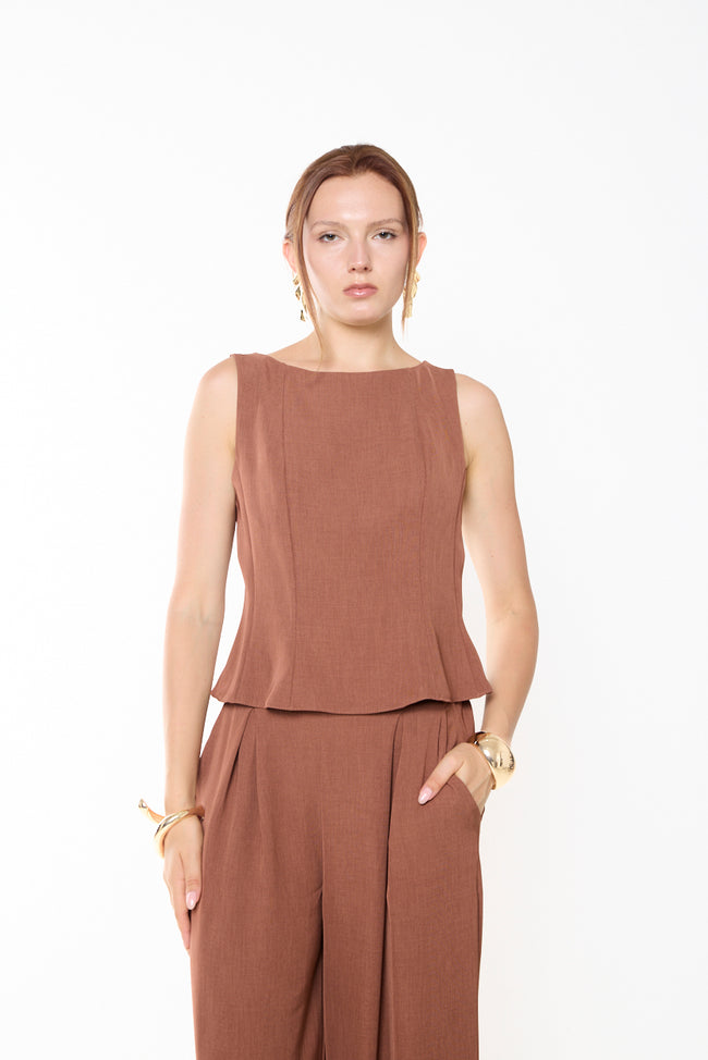 Camel rust fitted sleeveless peplum top with wide round neckline, shaped vertical bodice seams and flared hem; coordinating trousers and gold-tone accessories styled separately
