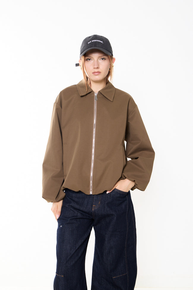 Camel brown zip-front blouson jacket with pointed collar, gathered sleeve ends, side welt pockets and relaxed cropped silhouette; jeans, cap and earrings styled separately