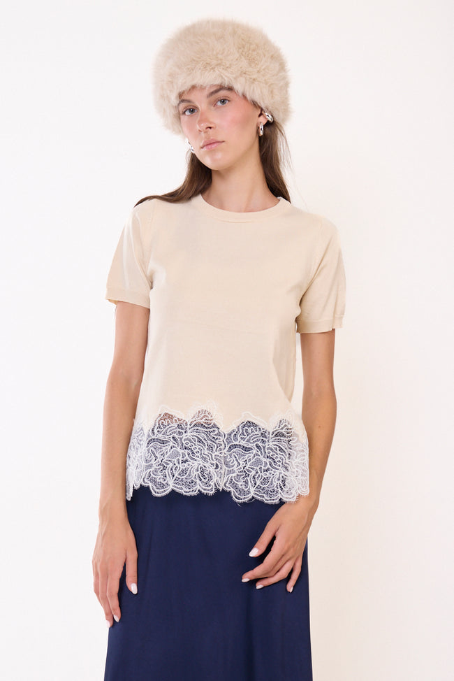 Beige round-neck short-sleeve knit T-shirt with floral lace hem panel and scalloped lace edge; navy skirt, hat and jewellery styled separately